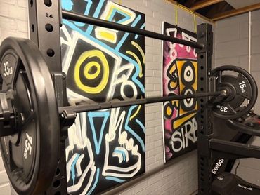 Weightlifting barbell with colorful graffiti art in a home gym.