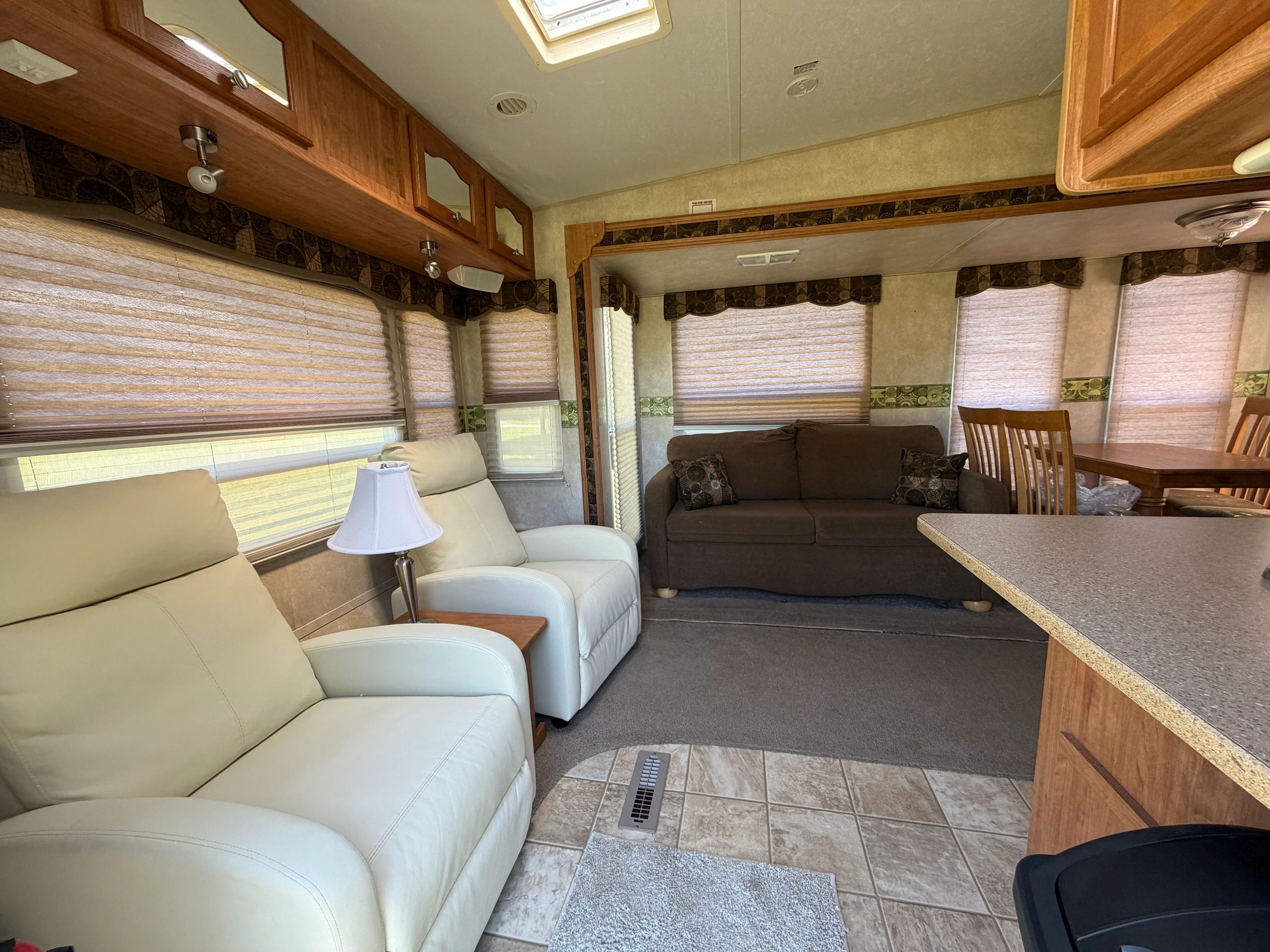 Cozy RV interior with reclining chairs, sofa, and dining area.
