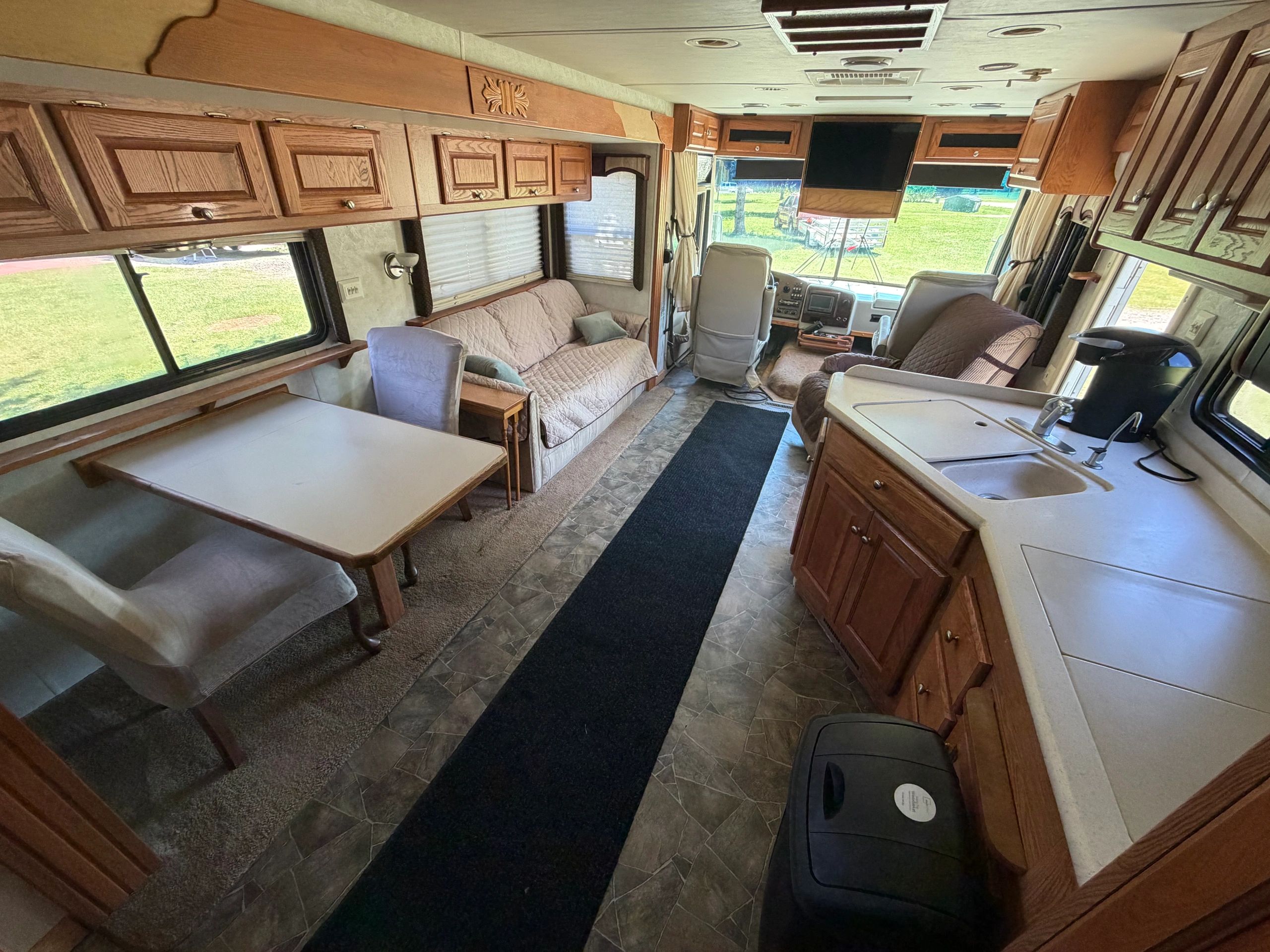 Interior of a cozy RV with wooden cabinets and seating area.