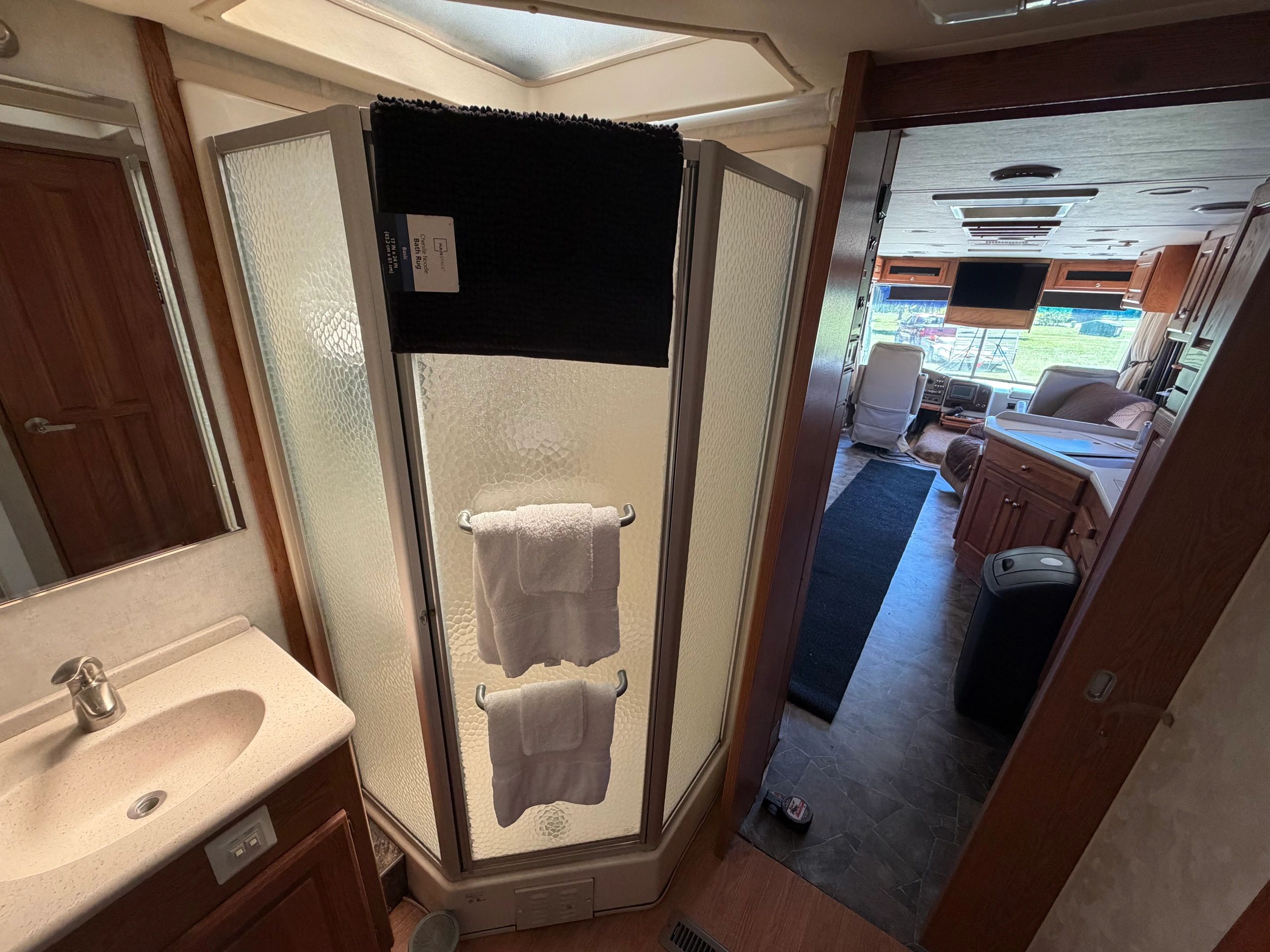 Interior of an RV showing bathroom and living area with natural light.