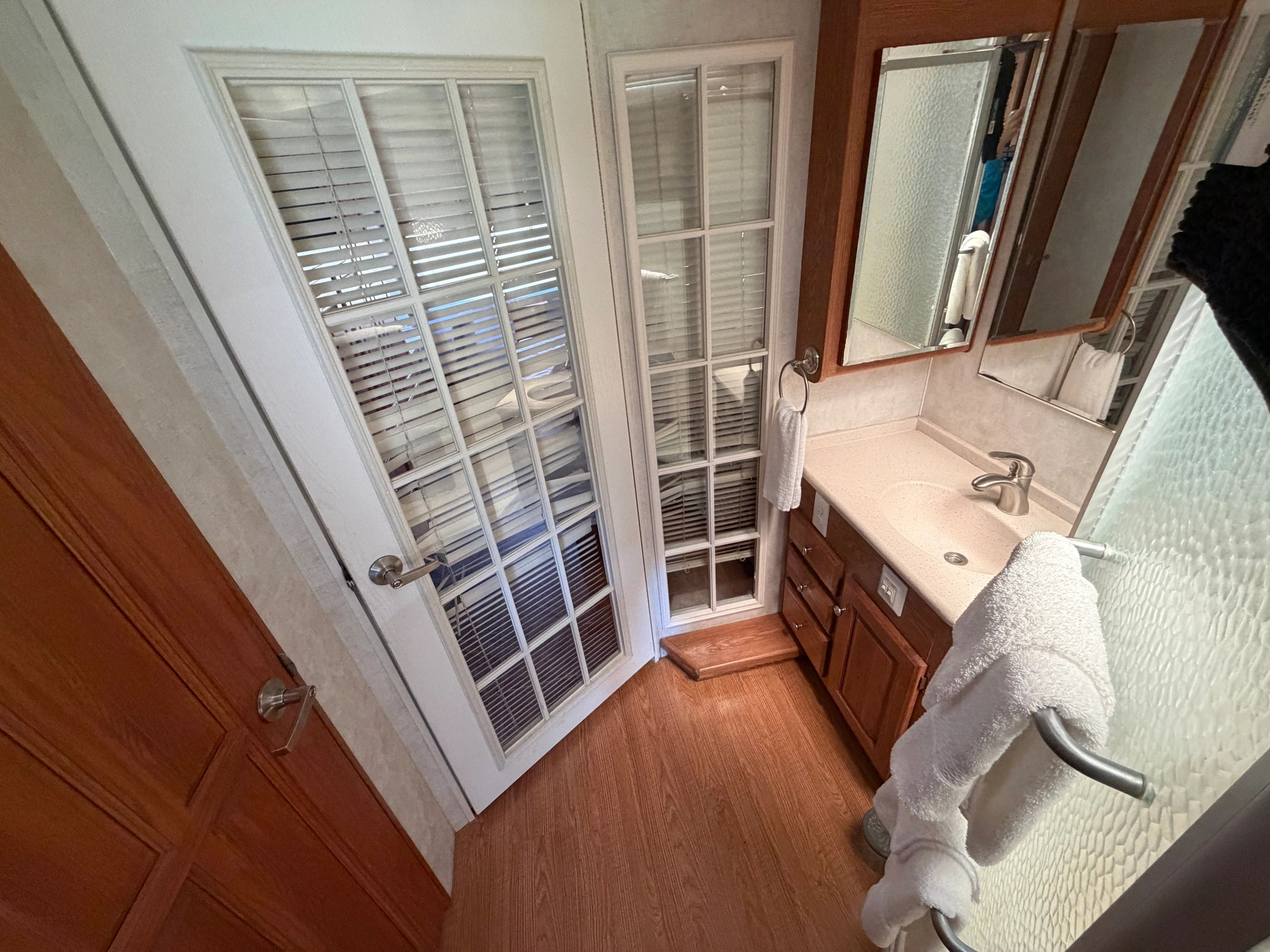 Cozy bathroom with wooden cabinets, glass-paneled door, and towel racks.