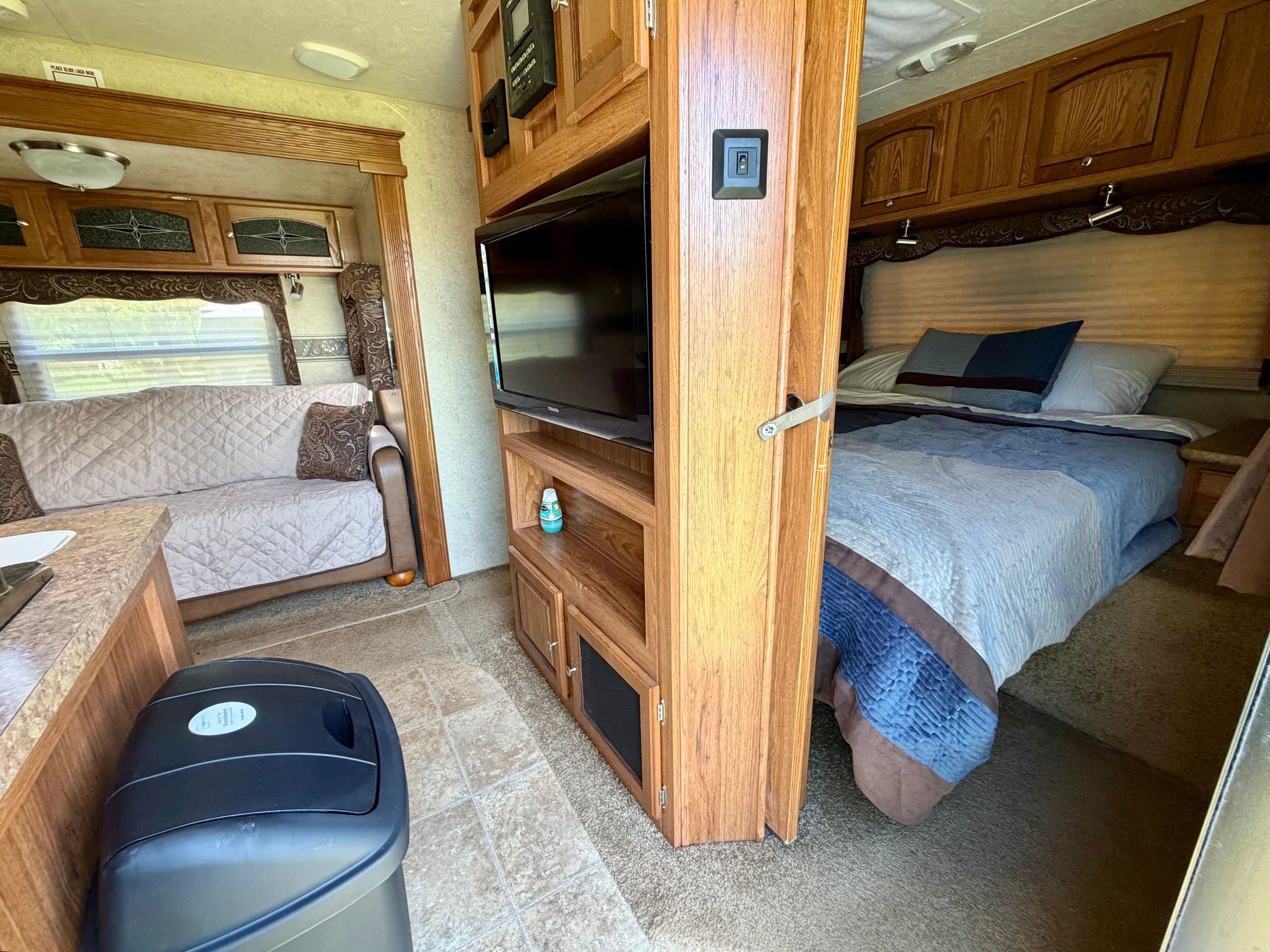 Interior of a cozy RV with a TV, sofa, and bed.