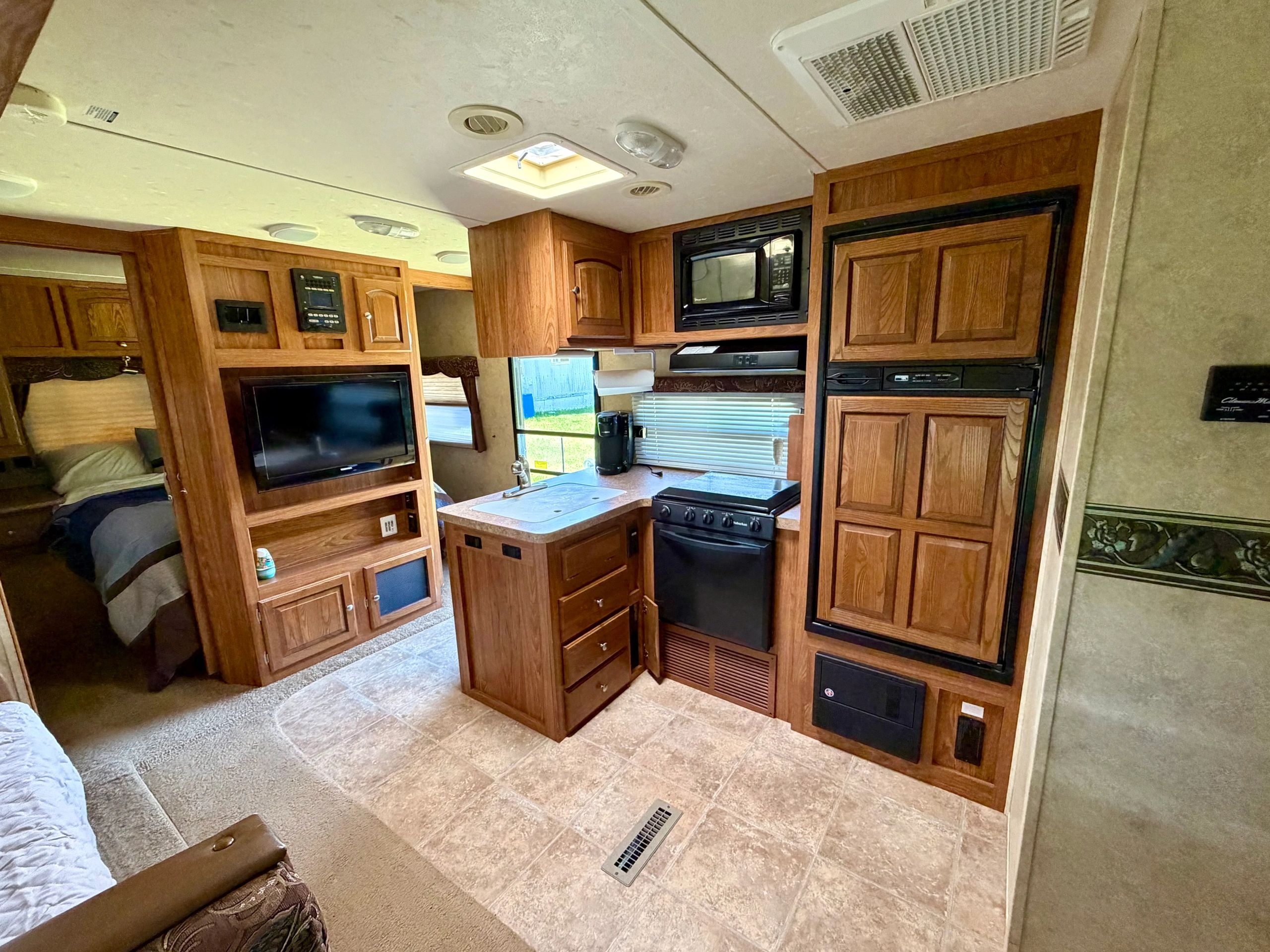 Interior of a cozy RV kitchen and living area with wooden cabinets and appliances.