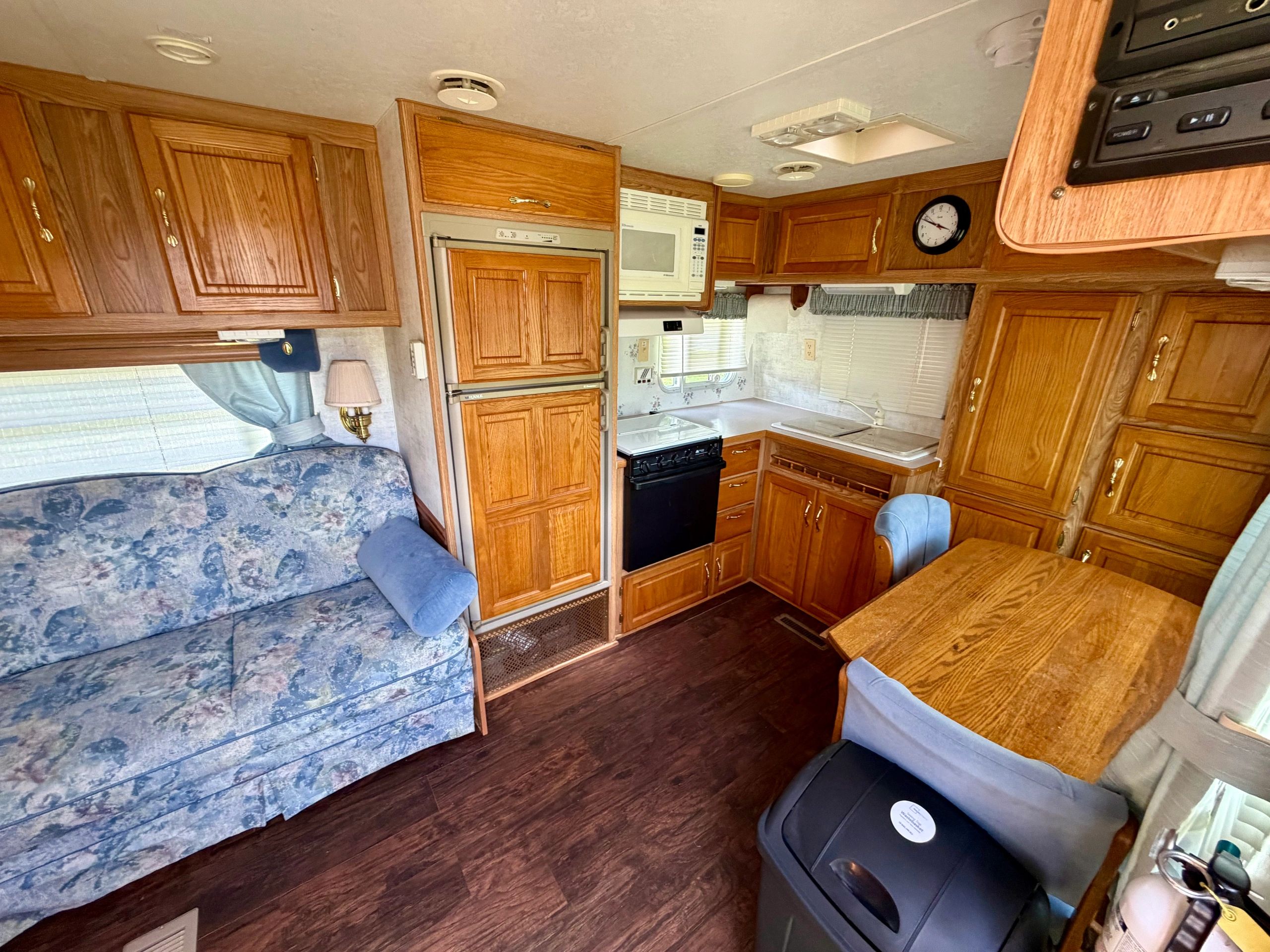 Cozy RV kitchen and living area with wooden cabinets and blue sofa.
