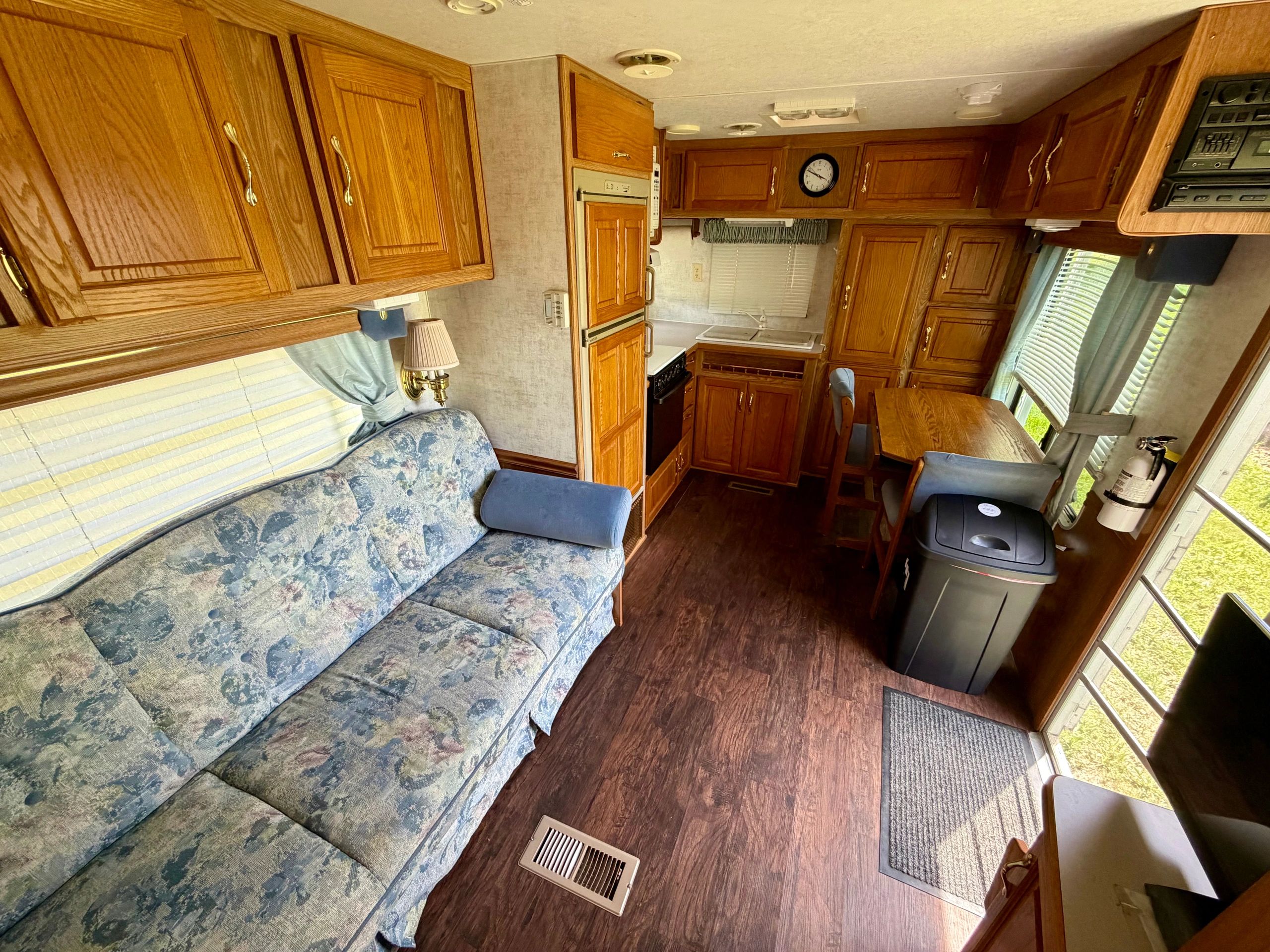 Cozy RV interior with wooden cabinets, floral sofa, and dining area.