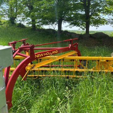 New Holland agricultural equipment in a grassy field.