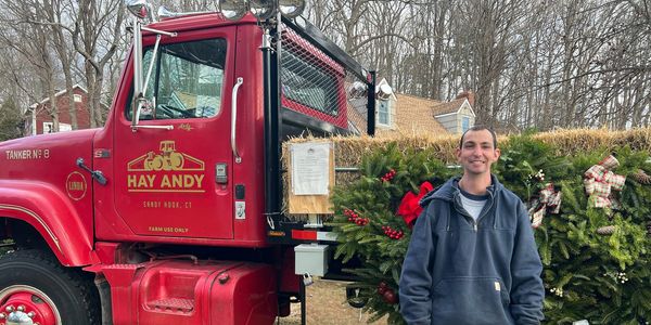 Young man standing by a decorated red farm truck.