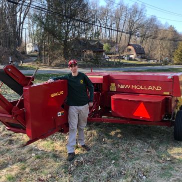 Man standing next to a red New Holland farm machine.