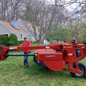 Man standing next to a red Case IH mower in a yard.