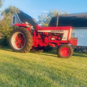 A red farm tractor on green grass.