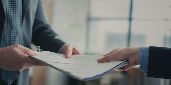 Two people exchanging documents in a business setting.