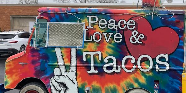Colorful food truck with "Peace, Love &amp; Tacos" text.