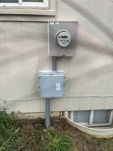 Electric meter and disconnect box on house exterior wall.