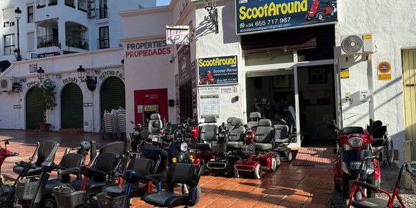 Scooter rental shop with mobility scooters lined up outside on a sunny day.