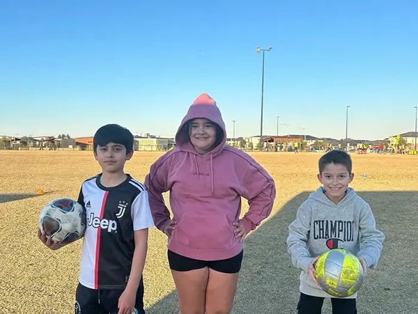 Group of children smiling at the camera on a football field