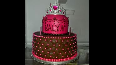 Two-tiered pink and brown birthday cake with a tiara on top.