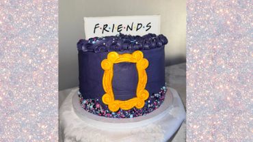 Purple cake with Friends TV show theme and yellow picture frame decoration.
