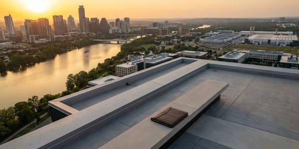 Sunset view of a city skyline and river from a rooftop terrace.