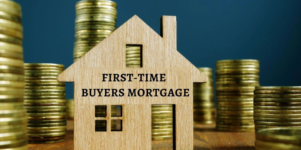 Wooden house model with 'First-Time Buyers Mortgage' text and stacks of coins in the background.