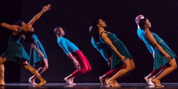 Dancers leaning backward in a synchronized performance on stage.