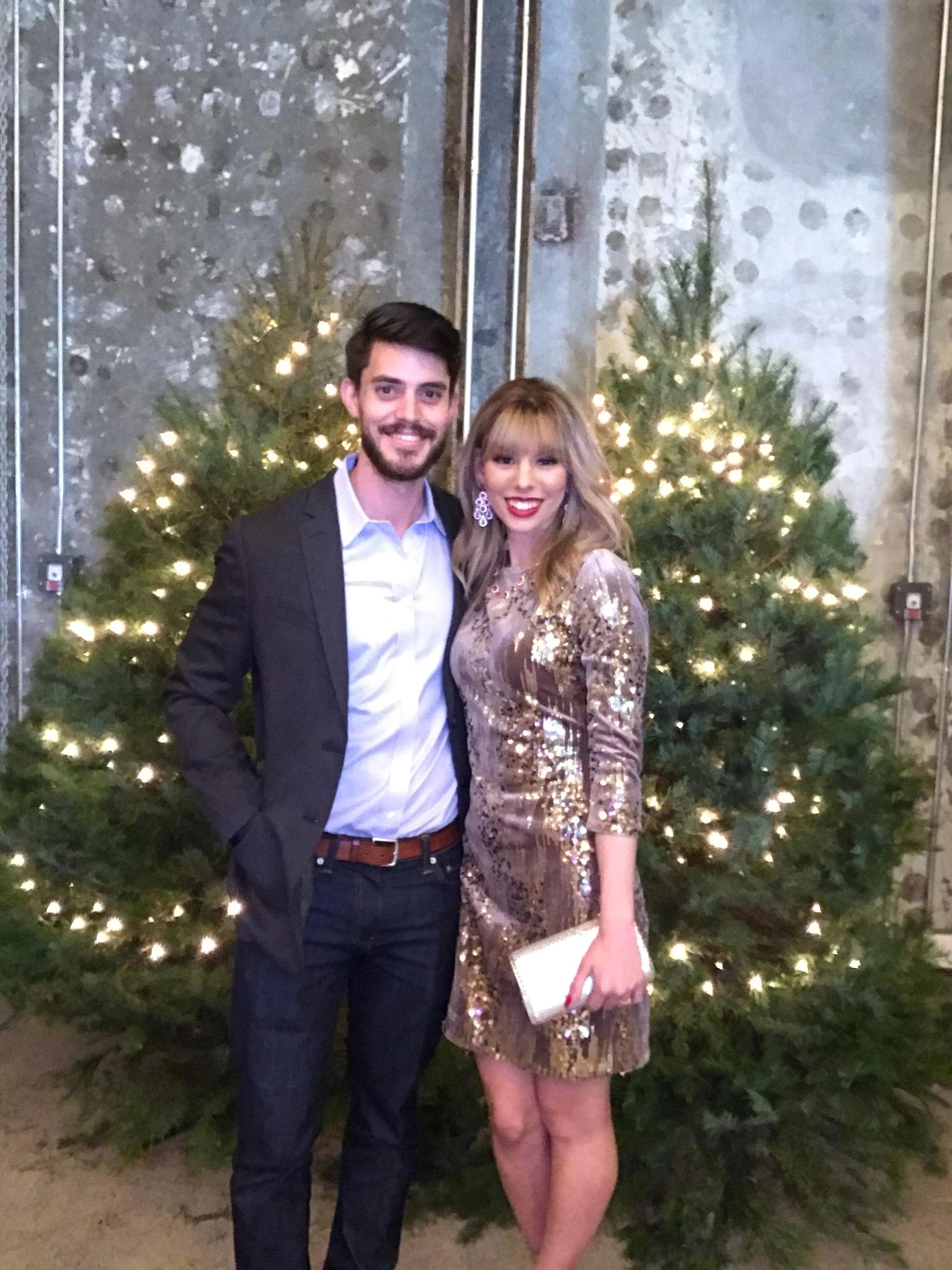 A man and a woman are posing for a picture in front of a christmas tree.