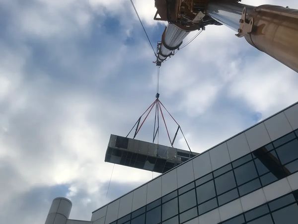 Mobile crane performing rooftop HVAC lift with engineered rigging configuration 
