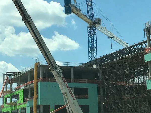 Tower crane and mobile crane coordinating lifts during large commercial building construction proje
