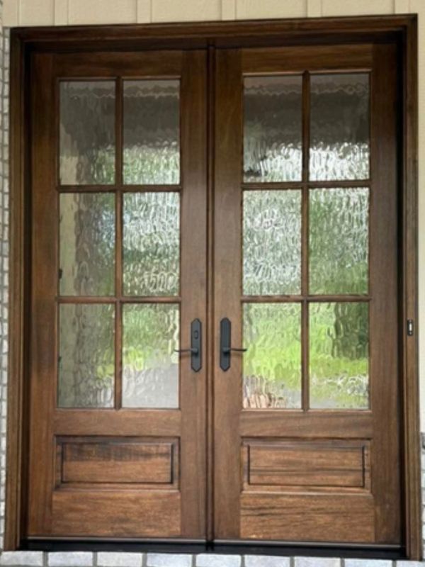 Double wooden doors with textured glass panels and black handles.