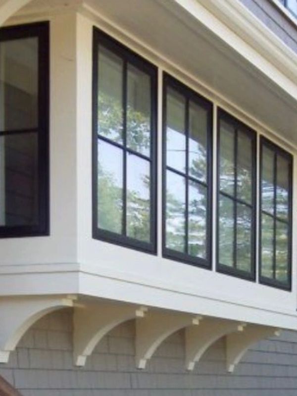 Modern bay window with black frames on a beige house.