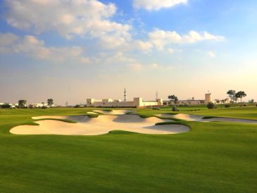 Golf course with sand bunkers under a partly cloudy sky.
