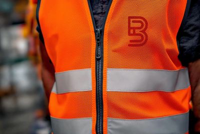 Close-up of a person wearing a bright orange reflective safety vest with a zipper.