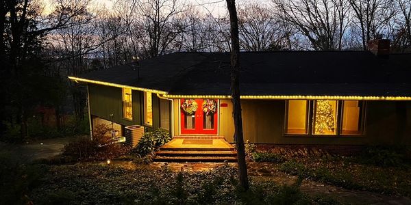 Cozy house decorated with Christmas lights and wreaths at twilight.