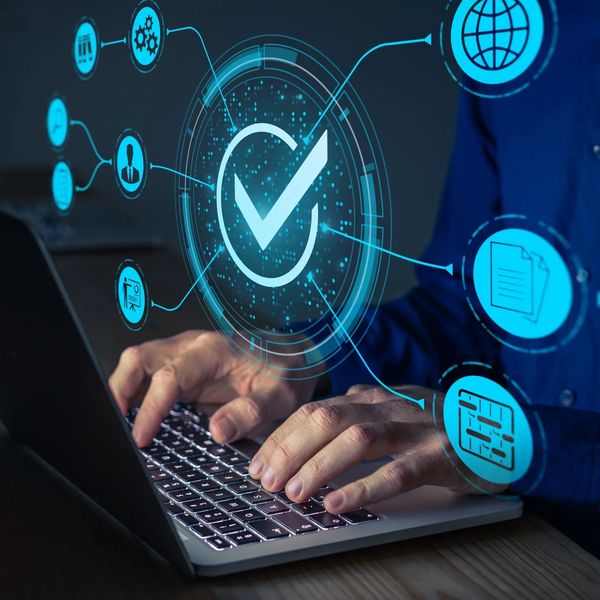 Person typing on laptop with digital quality control icons floating.