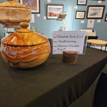 A wooden pistachio bowl with lid on display in an art gallery.