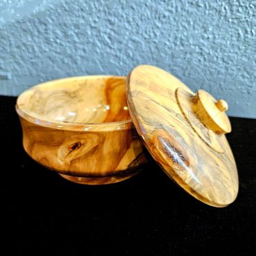 Wooden container with lid on a black surface.
