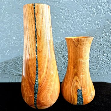 Handcrafted wooden vessels with resin inlay against a textured wall.