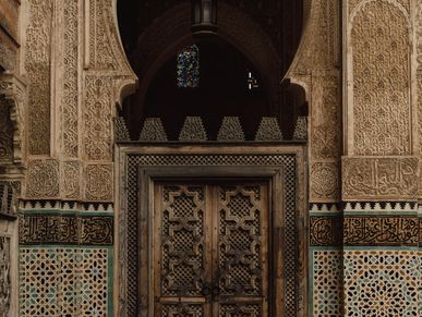 Intricately carved wooden door set in a detailed Moorish-style archway.
