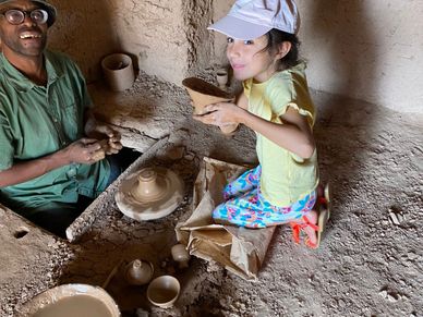 A man and a child happily making pottery together indoors.