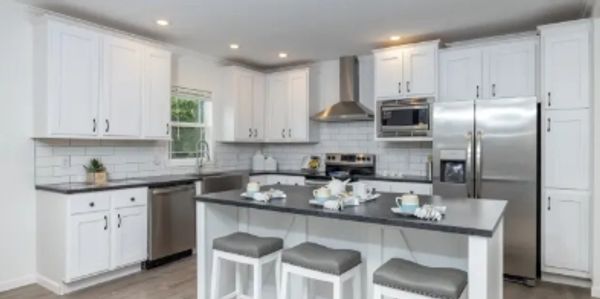 Modern white kitchen with stainless steel appliances and island seating.