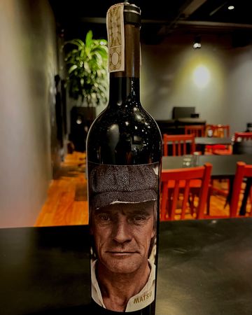 Bottle of wine with a label featuring a man's face wearing a cap.