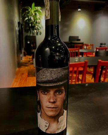 A wine bottle with a label featuring a young man wearing a patterned hat.