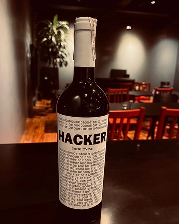 A wine bottle labeled 'HACKER Sangiovese' with binary code on the label.