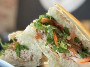 Fresh sandwich with turkey, greens, and roasted red peppers on soft bread.