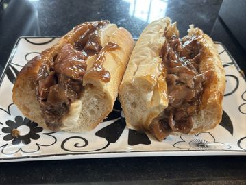 Two Philly cheesesteak sandwiches on a decorative plate.