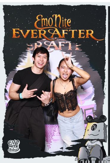 Young couple posing with rock hand signs at Emo Nite event.