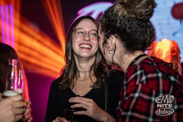 Two women enjoying a lively night out, smiling and chatting.