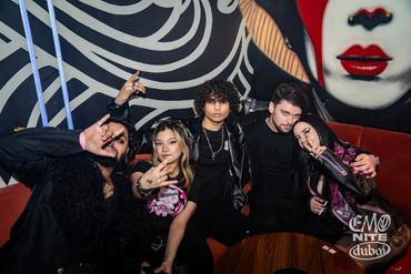 Group of young people posing in front of a vibrant mural at a club.