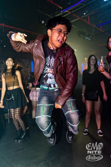 A man jumps energetically at a lively nightclub party in Dubai.