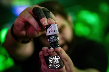 Person holding a small graffiti-covered figurine.
