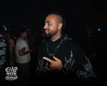 Man in black hoodie pointing, enjoying a night event at Emo Nite Dubai.